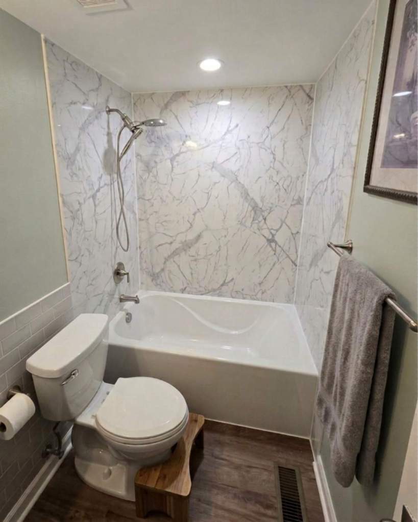 Bathtub and shower remodel featuring white marble-look wall surrounds, brushed nickel fixtures, and a deep soaking tub installed by The Bath Authority.