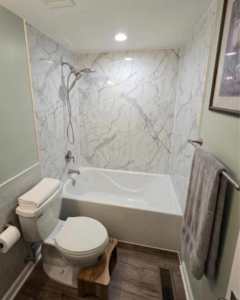 Bathtub and shower remodel featuring white marble-look wall surrounds, brushed nickel fixtures, and a deep soaking tub installed by The Bath Authority.