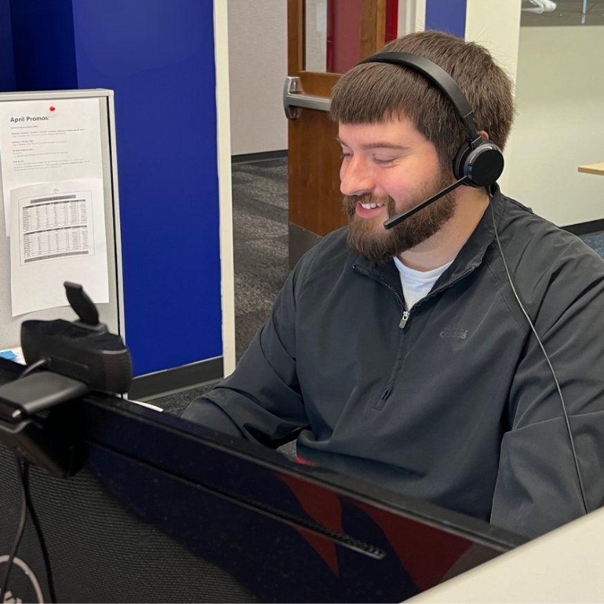 A man smiles as he answer a phone call with a headset.