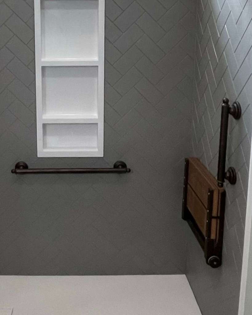 A wood-looking fold down shower seat with matte black hardware.