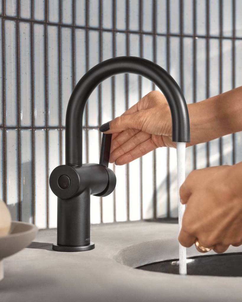 A close up shot of a hand turning on the water of a bathroom sink faucet.